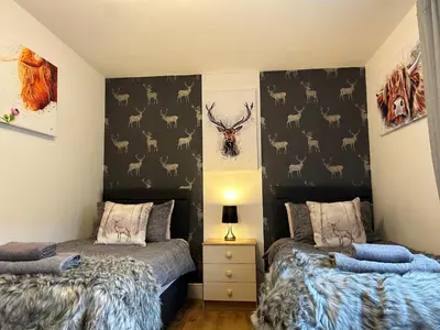 a bedroom with two beds and a wall with deer heads at Solway Cottage in Annan