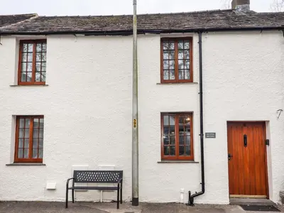 a white house with a bench in front of it at Fryston Cottage in Keswick