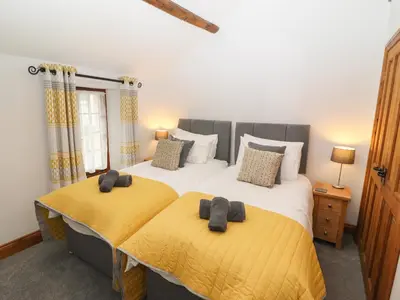 a bedroom with two beds with yellow sheets at Fryston Cottage in Keswick