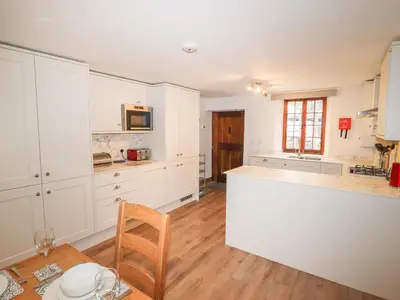 a kitchen with white cabinets and a wooden table at Fryston Cottage in Keswick