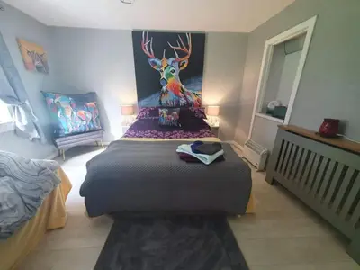 a bedroom with a bed with a deer painting on the wall at Modernised 1720s cottage Newton Stewart Scotland in Newton Stewart