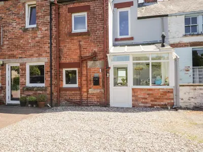 a brick house with a white door and windows at Pow-Wow Shore Cottage in Annan