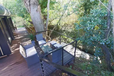 a porch with two chairs and a table on a deck at The Hide in Carlisle