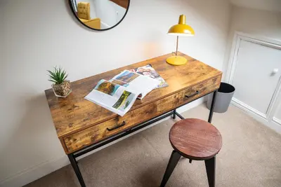 a wooden desk with a lamp and a chair at Luxury Studio Apartment - Town Centre in Whitehaven