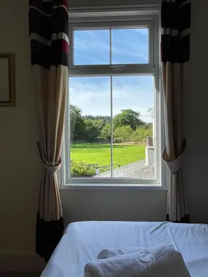 a bedroom window with a view of a green yard at Ouse Bridge House in Bassenthwaite Lake