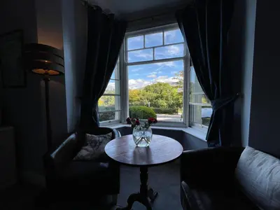 a living room with a table in front of a window at Ouse Bridge House in Bassenthwaite Lake