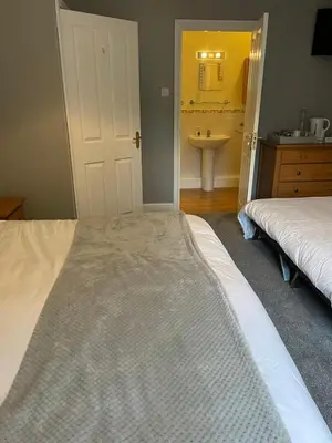 a bedroom with two beds and a sink and a mirror at Ouse Bridge House in Bassenthwaite Lake