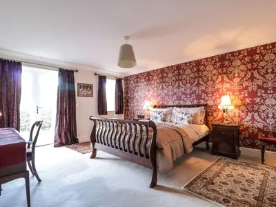 a bedroom with a large bed with red wallpaper at Cloud End in Keswick
