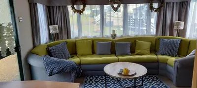 a living room with a green couch and a table at Westmorland 32 caravan in Ballantrae