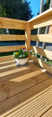 a wooden deck with a pot of flowers on it at Westmorland 32 caravan in Ballantrae