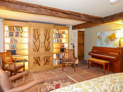 a living room with a piano and bookshelves at Eagle Farmhouse in Glenridding