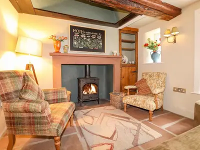 a living room with a fireplace and two chairs at Eagle Farmhouse in Glenridding