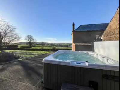 a hot tub in the backyard of a house at Woodend Farmhouse Halmyre in Haugh of Urr