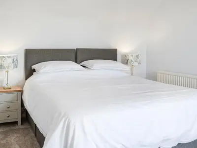 a large white bed with white sheets and pillows at Repentance View in Carrutherstown