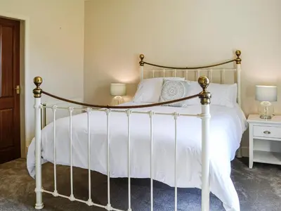 a bedroom with a white bed with a metal frame at Repentance View in Carrutherstown