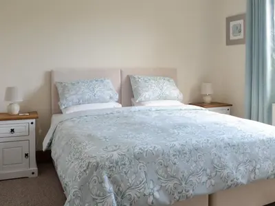 a bedroom with a bed with blue and white sheets and pillows at Stronvaar in Stranraer