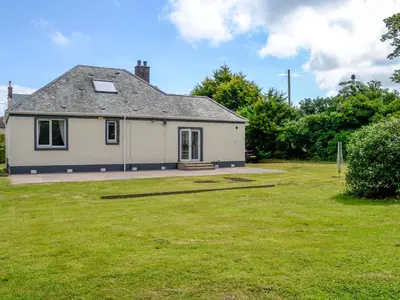 a small white house with a grass yard at Stronvaar in Stranraer