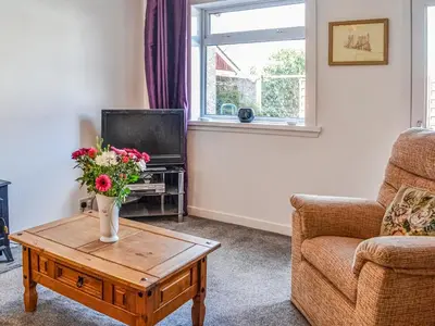 a living room with a vase of flowers on a coffee table at Ardencaple No 2 in Castle Douglas