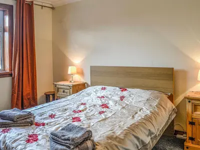 a bedroom with a large bed with red flowers on it at Ardencaple No 2 in Castle Douglas