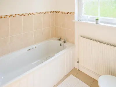 a bathroom with a white tub and a toilet at Arden Cottage in Twynholm