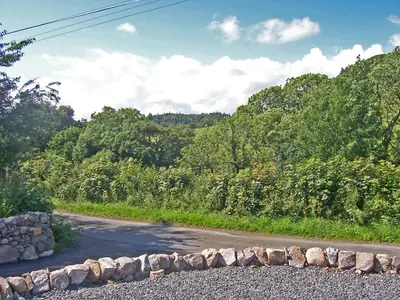 a road with a stone wall on the side of it at Arden Cottage in Twynholm