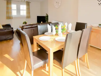 a dining room with a wooden table and chairs at Arden Cottage in Twynholm