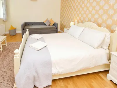 a bedroom with a white bed and a couch at Arden Cottage in Twynholm