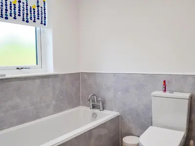 a bathroom with a tub and a toilet and a window at Inverallan in Amisfield Town