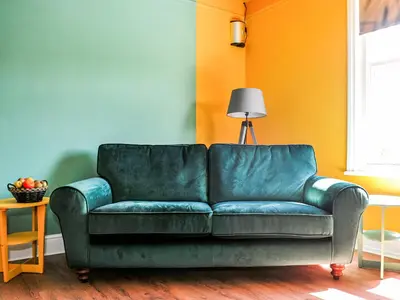 a green couch in a living room with an orange wall at Holst Apartment in Newton Stewart