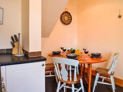 a kitchen with a wooden table with glasses of wine at Hammy's Cottage in Drummore