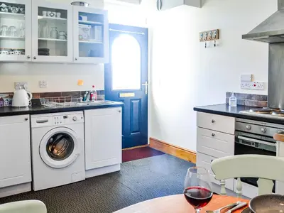 a kitchen with a washing machine and a blue door at Hammy's Cottage in Drummore