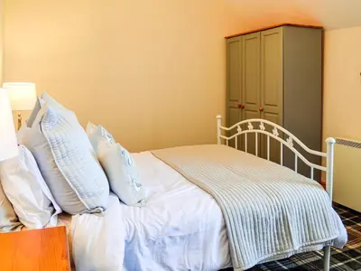a bedroom with a bed with white sheets and pillows at Hammy's Cottage in Drummore