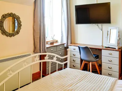 a bedroom with a bed and a desk and a chair at Hammy's Cottage in Drummore