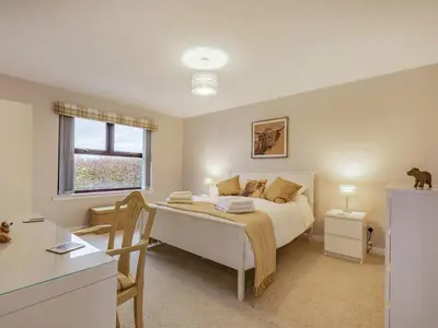 a bedroom with a bed and a table and a window at Rowan Muir in Springside