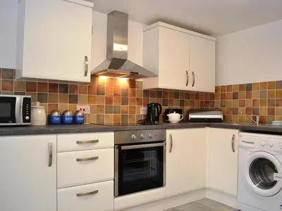 a kitchen with white cabinets and a washer and dryer at Shepherds Cottage in Corney