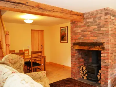 a living room with a brick fireplace and a table at Shepherds Cottage in Corney