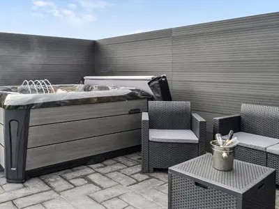 a patio with a hot tub and two chairs at The Seaview Snug in Whithorn