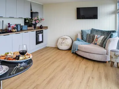 a living room with a couch and a table with a glass of wine at The Seaview Snug in Whithorn