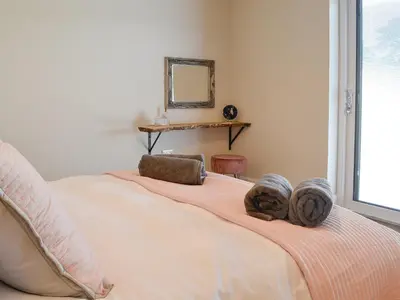 a bedroom with a bed with a mirror and a window at The Byre in Castle Douglas