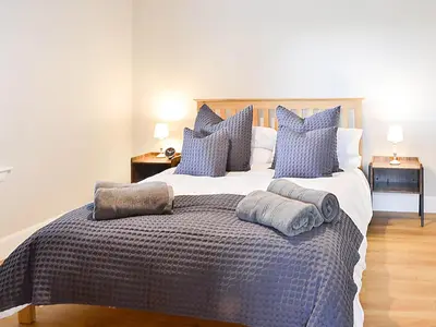 a bedroom with a large bed with blue pillows at The Byre in Castle Douglas
