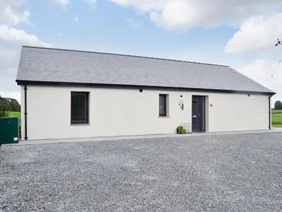 a white building with a black roof at The Byre in Castle Douglas