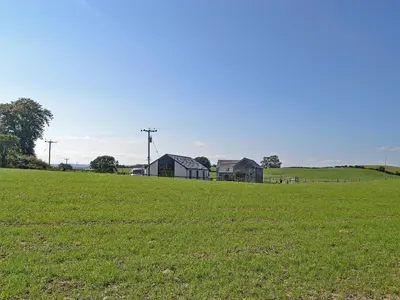 a green field with houses in the background at The Byre in Castle Douglas