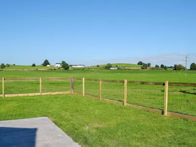 a fence in the middle of a field with a pasture at The Byre in Castle Douglas