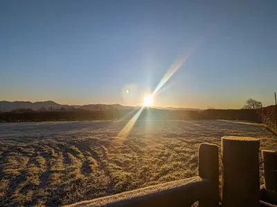 a sun setting over a snow covered field at High Mains in Winscales
