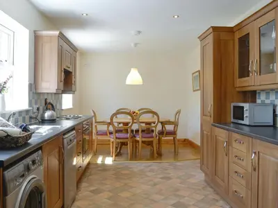 a kitchen with wooden cabinets and a table and chairs at Curlew Cottage in Dinwoodie Mains