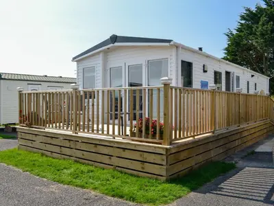 a house on a wooden deck with a fence at Loch View in Kirkcolm