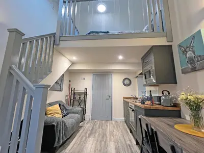 a living room with a staircase and a kitchen with a couch at Uk7384 - The Hayloft in Newmilns