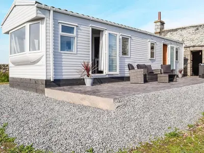 a white house with chairs and a patio at The Seaview Retreat - Uk35883 in Broughton Mains