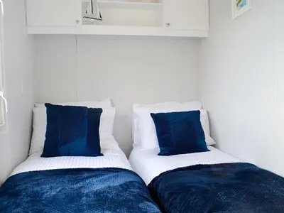 two beds with blue pillows sitting next to each other at The Seaview Retreat - Uk35883 in Broughton Mains