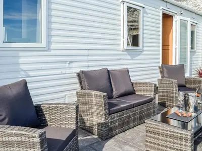 a group of wicker chairs and a table on a patio at The Seaview Retreat - Uk35883 in Broughton Mains